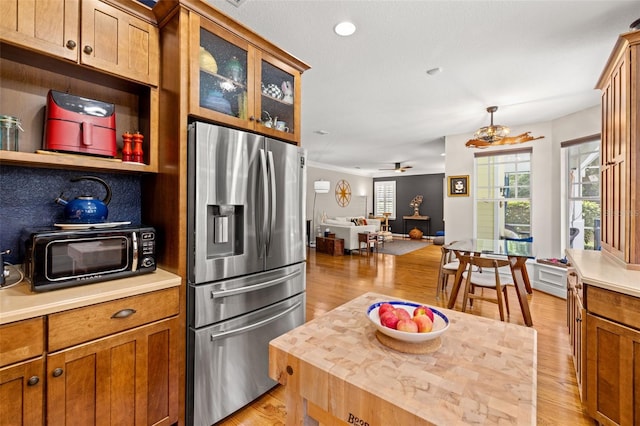 5902 Audubon Manor Blvd, Lithia, FL 33547 - kitchen featuring stainless steel fridge with ice dispenser, light wood-style flooring, brown cabinets, ceiling fan, and glass insert cabinets
