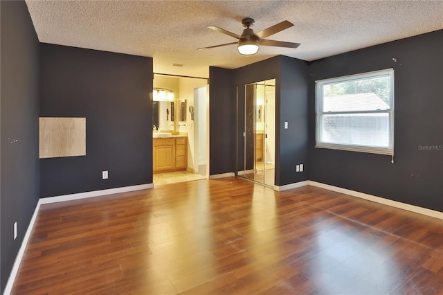 1915 Peppertree Dr, Oldsmar, FL 34677 - unfurnished bedroom featuring a textured ceiling, wood finished floors, ensuite bath, ceiling fan, and baseboards