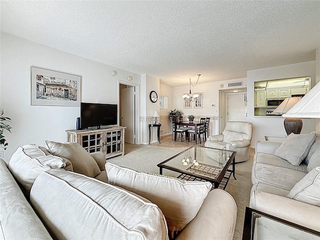 living area with light carpet, a chandelier, a textured ceiling, and visible vents