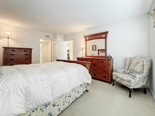 bedroom with light carpet, a textured ceiling, and visible vents