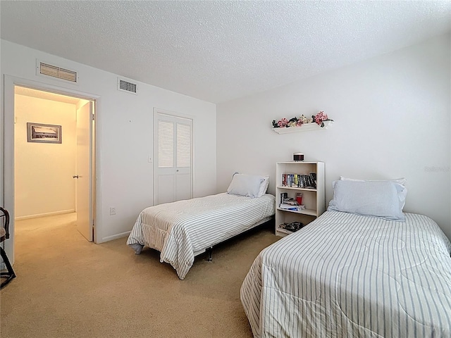 carpeted bedroom featuring visible vents, a textured ceiling, and a closet