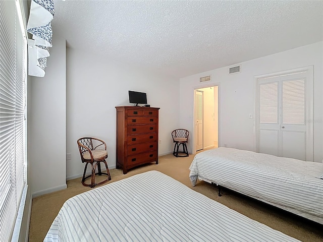 bedroom featuring light colored carpet, a textured ceiling, and visible vents