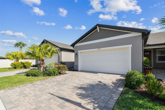 ranch-style home featuring a garage, fence, stucco siding, and decorative driveway