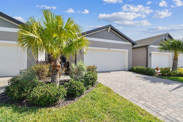 single story home with stucco siding, decorative driveway, and a garage