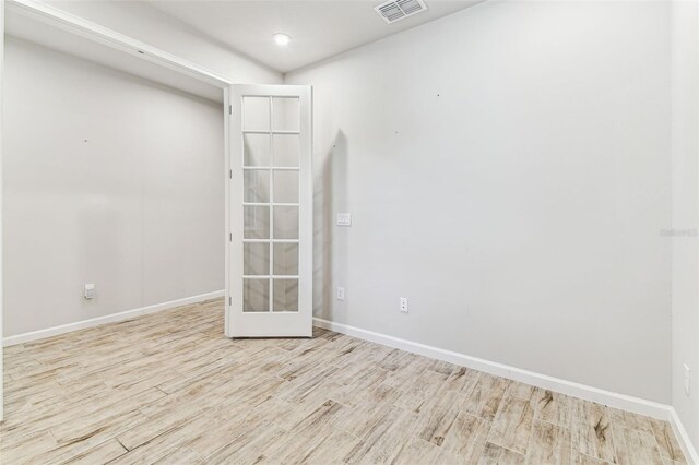 spare room featuring baseboards, visible vents, wood finished floors, and french doors