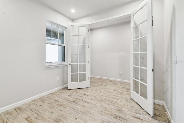 empty room with baseboards, wood finished floors, and french doors