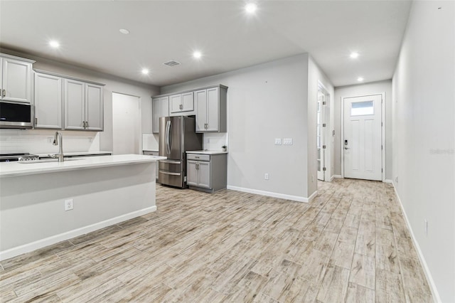 kitchen featuring recessed lighting, appliances with stainless steel finishes, light countertops, a sink, and gray cabinetry