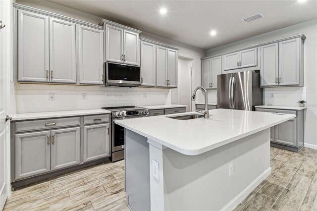 kitchen with gray cabinets, recessed lighting, appliances with stainless steel finishes, a sink, and visible vents