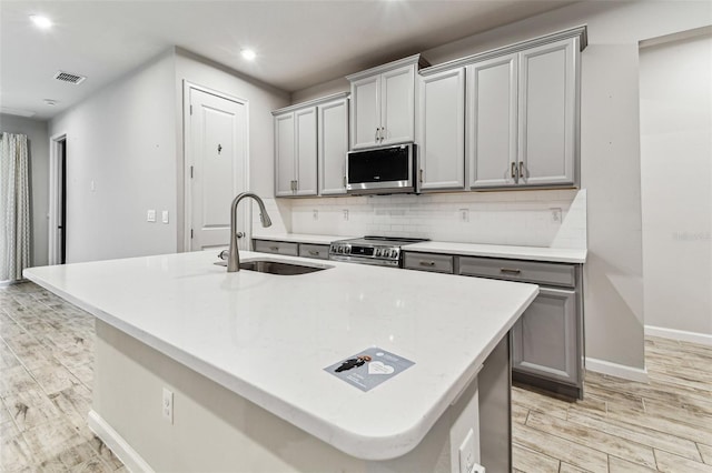 kitchen featuring gray cabinetry, a sink, stainless steel electric range oven, and visible vents
