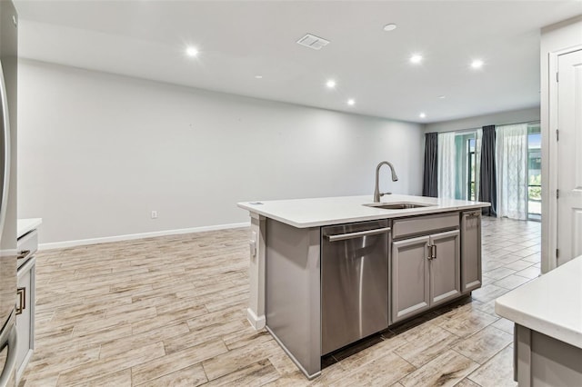 kitchen featuring a sink, light wood-style flooring, light countertops, stainless steel dishwasher, and gray cabinetry