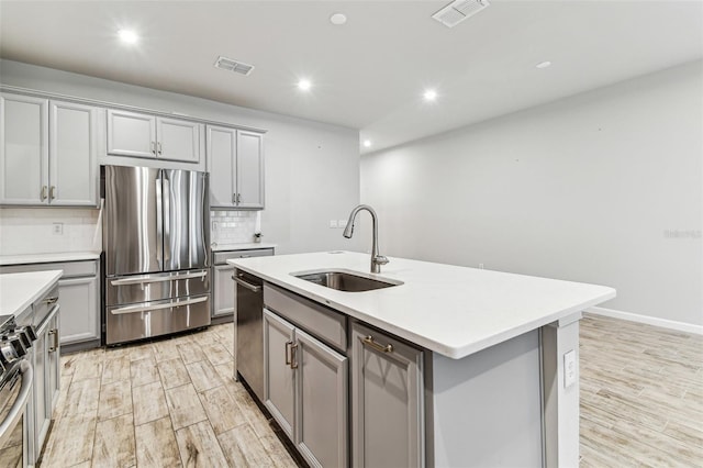 kitchen with appliances with stainless steel finishes, visible vents, gray cabinetry, and a sink