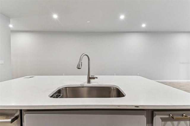 kitchen with recessed lighting, light stone countertops, a sink, and an island with sink