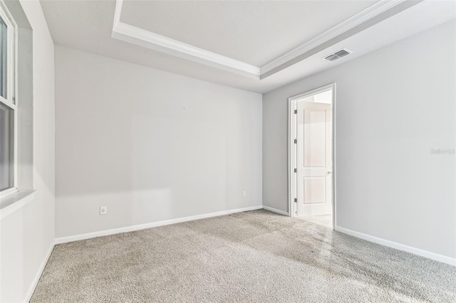 carpeted empty room with baseboards, visible vents, and a tray ceiling