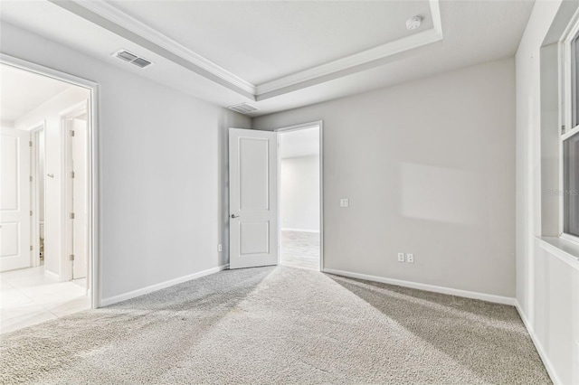 unfurnished bedroom with baseboards, visible vents, carpet, and a tray ceiling