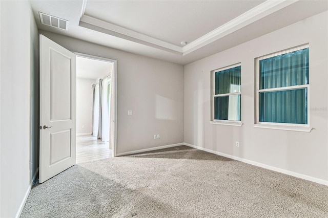 unfurnished room featuring ornamental molding, carpet flooring, baseboards, visible vents, and a tray ceiling