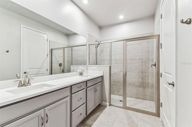 bathroom featuring a shower stall, tile patterned flooring, double vanity, and a sink