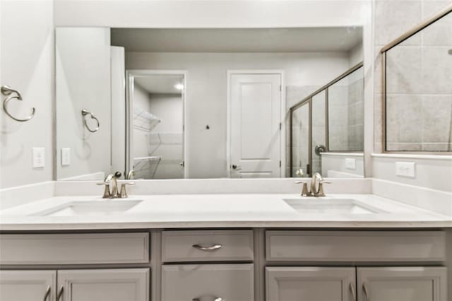 bathroom featuring a shower stall, double vanity, and a sink