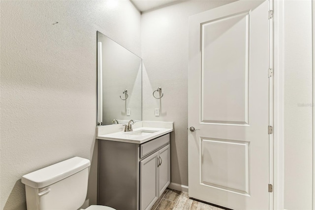 bathroom with toilet, wood finished floors, and vanity