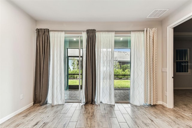 spare room with wood finished floors, plenty of natural light, and visible vents
