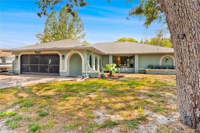 back of property featuring a garage, roof with shingles, concrete driveway, and stucco siding