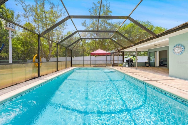 view of swimming pool with glass enclosure, a fenced in pool, a fenced backyard, and a patio