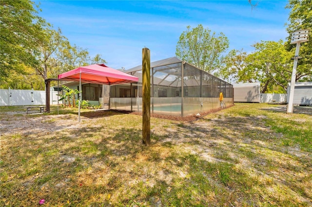 view of yard with glass enclosure, a fenced backyard, an outdoor structure, a fenced in pool, and a storage unit