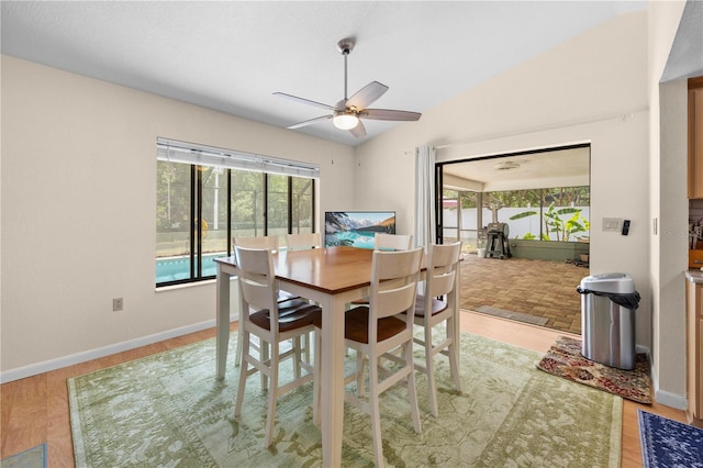 dining space featuring lofted ceiling, a ceiling fan, baseboards, and wood finished floors