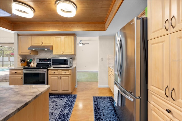 kitchen with light brown cabinetry, light wood-type flooring, stainless steel appliances, baseboards, and under cabinet range hood