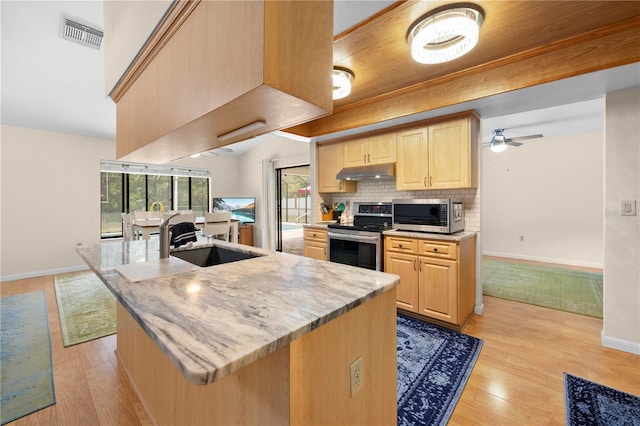 kitchen with a sink, visible vents, light brown cabinets, under cabinet range hood, and appliances with stainless steel finishes