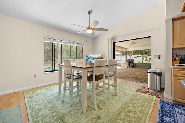 dining space featuring light wood finished floors, lofted ceiling, a ceiling fan, and baseboards