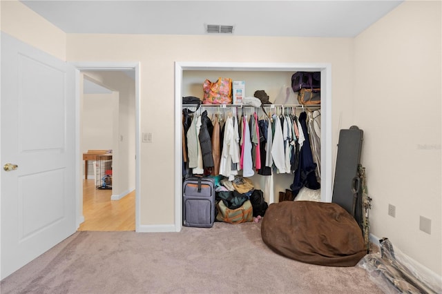 bedroom with a closet, carpet floors, visible vents, and baseboards