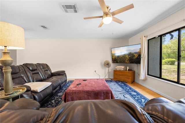 living room featuring wood finished floors, visible vents, a ceiling fan, and baseboards