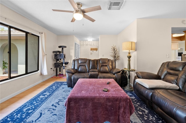 living room featuring wood finished floors, baseboards, a ceiling fan, and visible vents