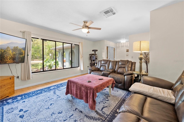 living area with wood finished floors, baseboards, a ceiling fan, and visible vents