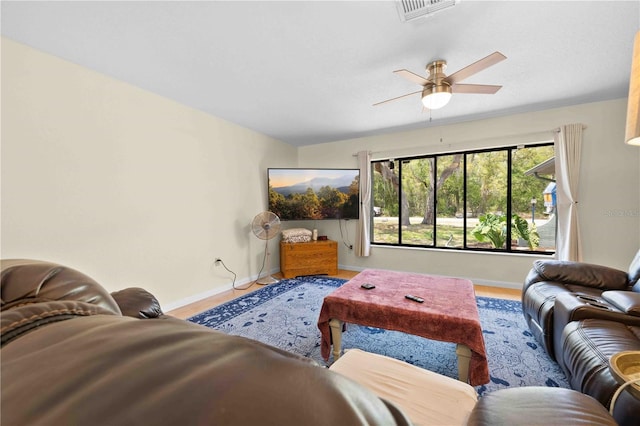 living area featuring baseboards, a ceiling fan, and visible vents