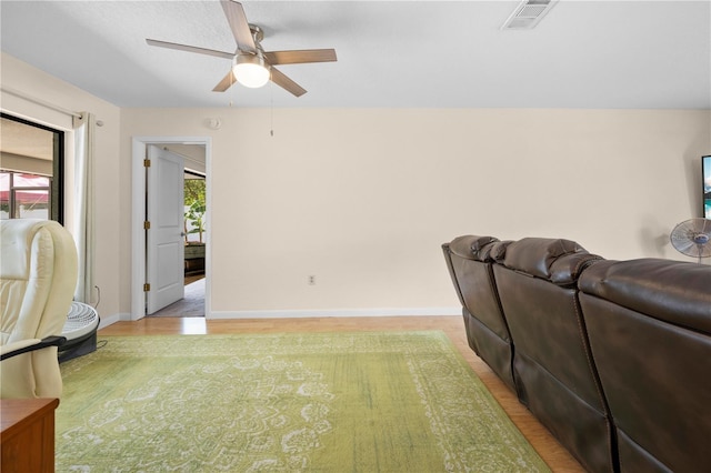 living area with baseboards, a ceiling fan, visible vents, and light wood-type flooring