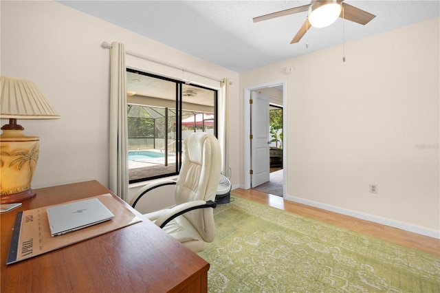 office area featuring light wood-type flooring, a ceiling fan, baseboards, and a healthy amount of sunlight