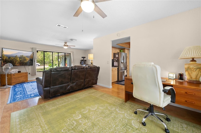 office with light wood-type flooring, baseboards, a ceiling fan, and visible vents