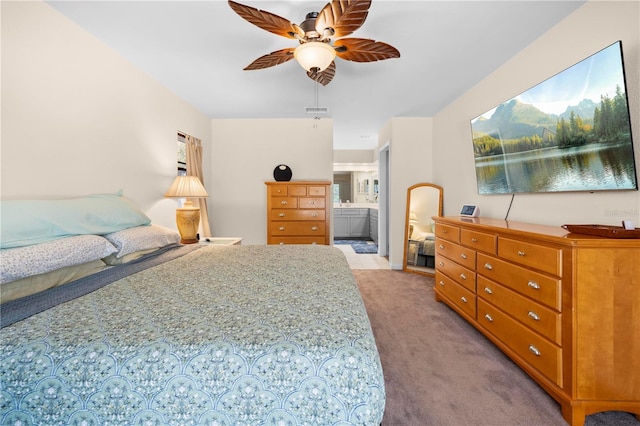 bedroom with ensuite bath, visible vents, light colored carpet, and ceiling fan