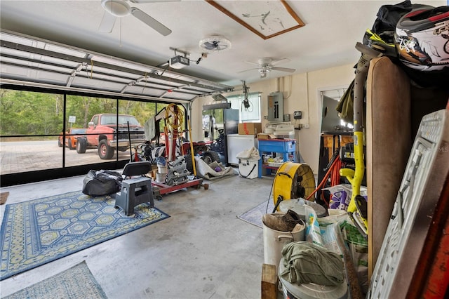 garage featuring electric panel, a ceiling fan, a garage door opener, and black fridge