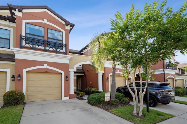 view of front of home featuring stucco siding, a balcony, and concrete driveway