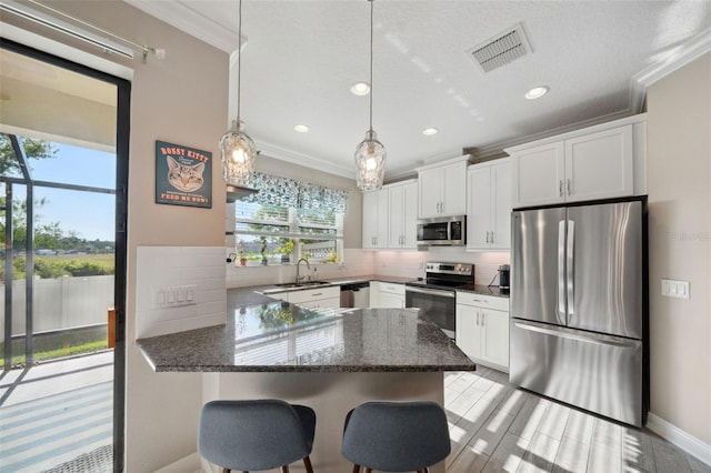 kitchen featuring crown molding, stainless steel appliances, visible vents, and a peninsula