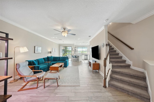 living room featuring ceiling fan, ornamental molding, and stairs