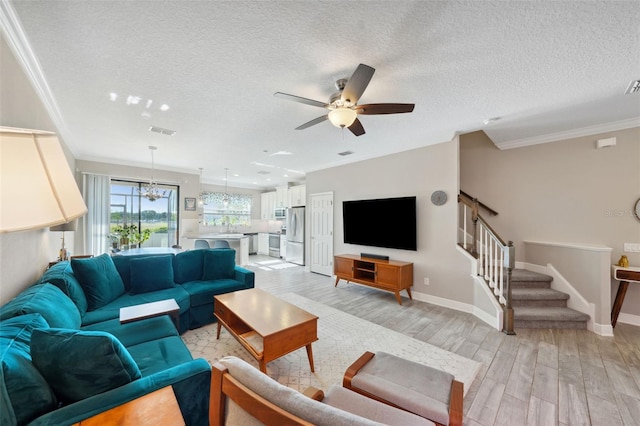 living area featuring ceiling fan, a textured ceiling, visible vents, crown molding, and light wood-style flooring