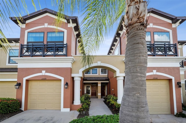 view of front of house with an attached garage, stucco siding, a balcony, and concrete driveway