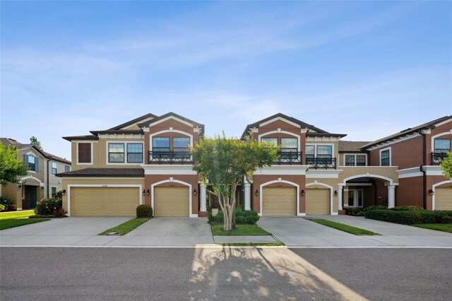 view of front of property with a garage, stucco siding, concrete driveway, and a balcony