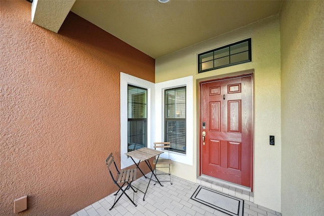 property entrance with covered porch and stucco siding