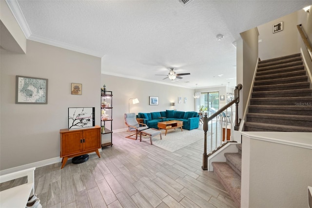 living area with light wood-style floors, ceiling fan, ornamental molding, and stairs