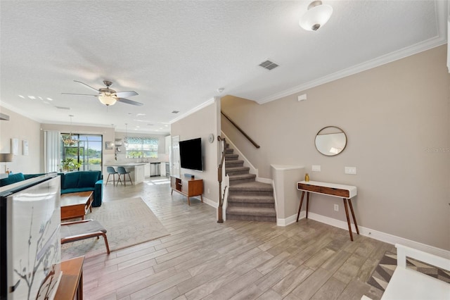 living area featuring visible vents, ornamental molding, stairway, a ceiling fan, and light wood finished floors