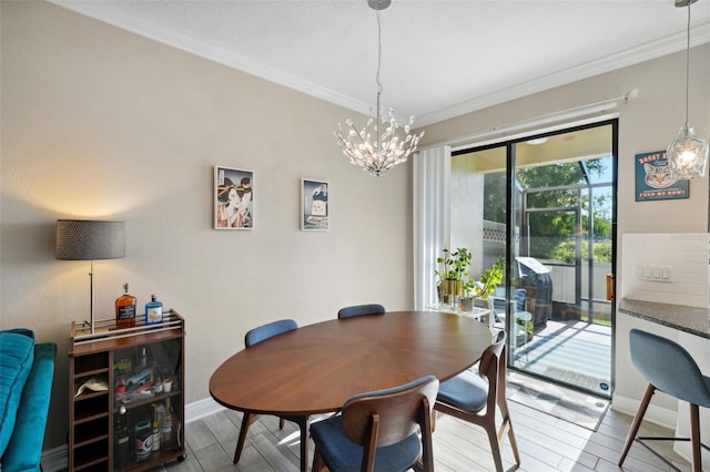 dining area featuring baseboards, ornamental molding, wood finished floors, and a notable chandelier